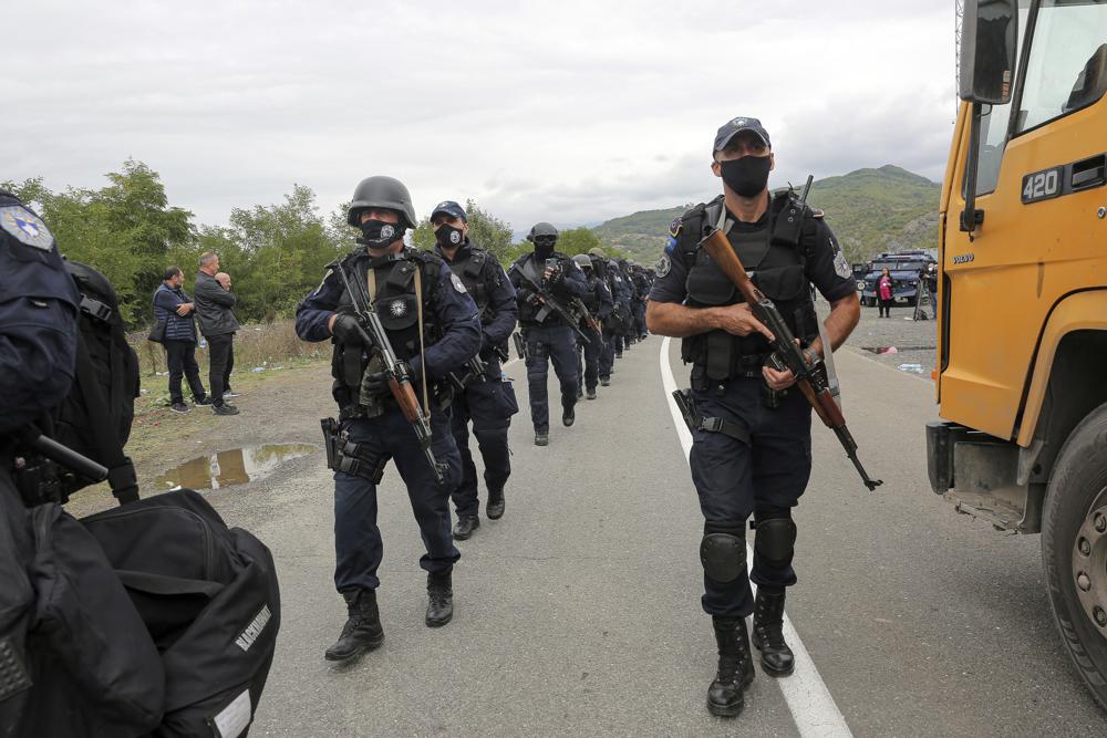 Kosovo police officers walk to replace their colleagues near the northern Kosovo border crossing of Jarinje on Tuesday, Sept. 21, 2021. Tensions soared Monday when Kosovo special police with armored vehicles were sent to the border to impose a rule on temporarily replacing Serb license plates from cars while they drive in Kosovo. (AP Photo/Visar Kryeziu)