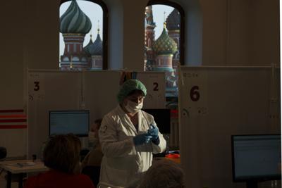 Una trabajadora médica prepara una dosis de la vacuna rusa contra el COVID-19 Sputnik Lite, en un centro de vacunación en una tienda GUM, en la Plaza Roja, con la catedral de San Basilio al fondo, en Moscú, Rusia, el 26 de octubre de 2021. (AP Foto/Pavel Golovkin)