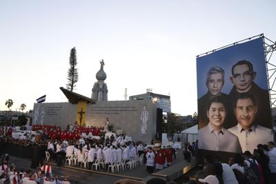 Un mural con las imágenes del reverendo Rutilio Grande, el sacerdote franciscano Cosme Spessotto, y los laicos Nelson Lemus y Manuel Lémus, todos ellos asesinados por escuadrones de la muerte durante la guerra civil de El Salvador, es exhibido durante la ceremonia de su beatificación en San Salvador, el sábado 22 de enero de 2022. (AP Foto/Salvador Melendez)