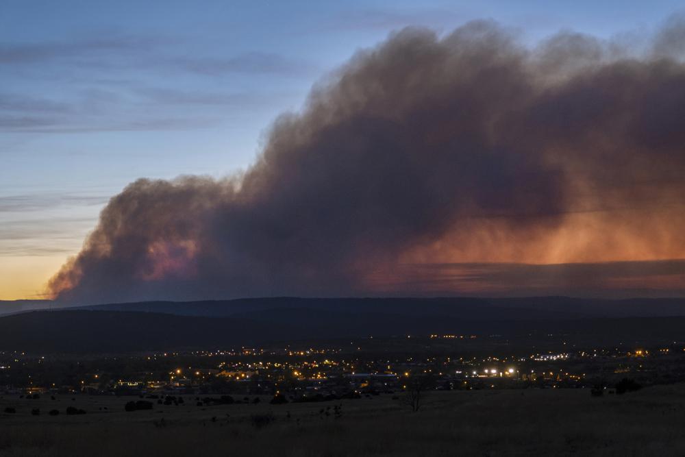 FILE - Smoke from the Calf Canyon/Hermits Peak Fire drifts over Las Vegas, N.M., on May 7, 2022. New Mexico Gov. Michelle Lujan Grisham on Monday, Feb. 20, 2023, signed a law to use zero-interest loans to help local governments in the arid, Southwest state repair or replace public infrastructure damaged by wildfires or subsequent flooding. (Robert Browman/The Albuquerque Journal via AP, File)