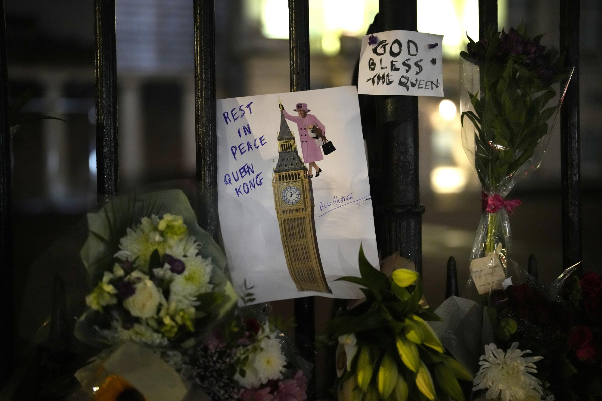 A draw of Britain's Queen Elizabeth II is placed with flowers outside Buckingham Palace in London, Friday, Sept. 9, 2022. Queen Elizabeth II, Britain's longest-reigning monarch and a rock of stability across much of a turbulent century, died Thursday after 70 years on the throne. She was 96. (AP Photo/Christophe Ena)