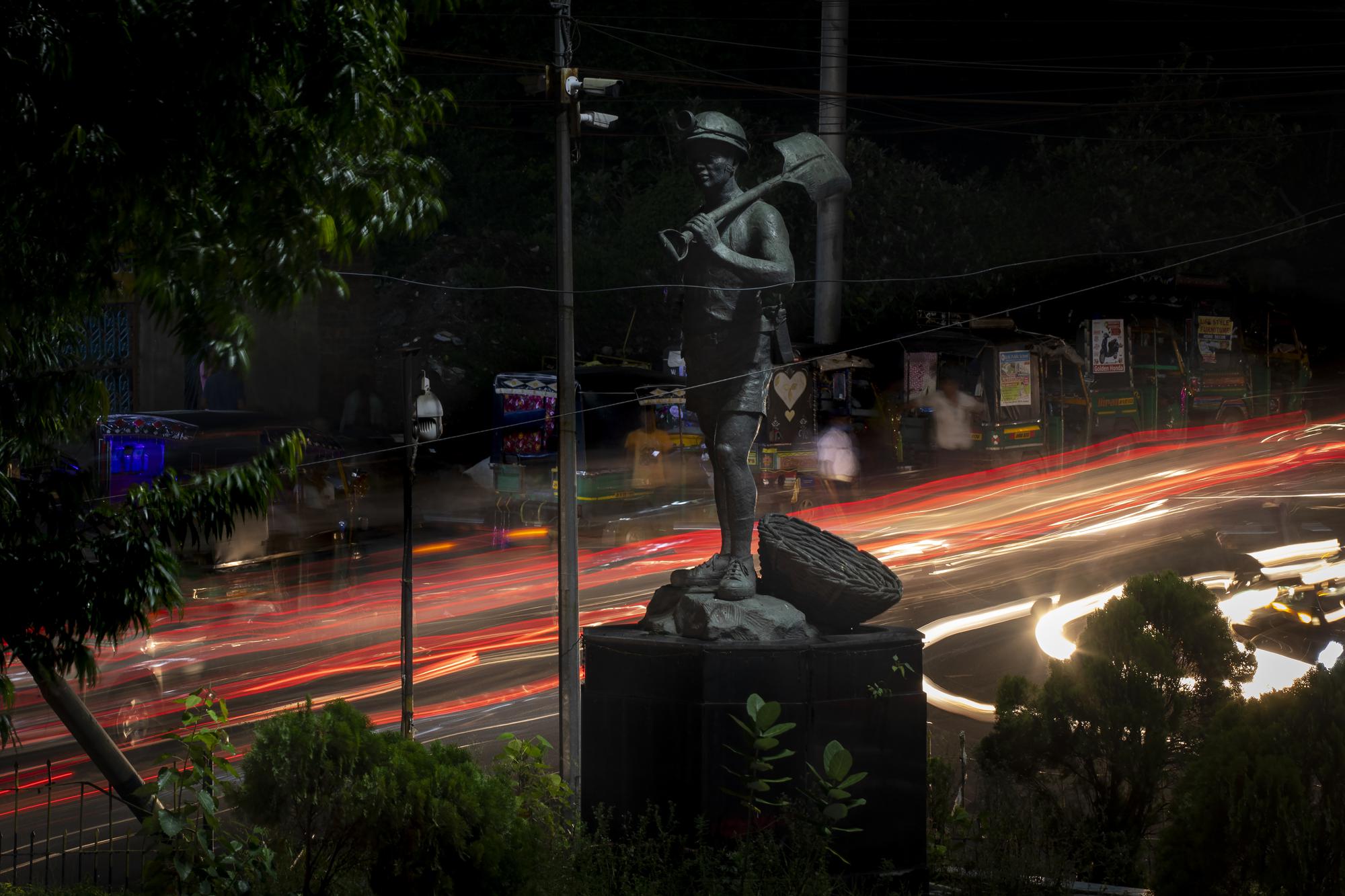 Light trails are left by passing traffic as they drive past the statue of an unknown coal miner in the middle of a square in Dhanbad, an eastern Indian city in Jharkhand state, Thursday, Sept. 23, 2021. A 2021 Indian government study found that Jharkhand state -- among the poorest in India and the state with the nation’s largest coal reserves -- is also the most vulnerable Indian state to climate change. Efforts to fight climate change are being held back in part because coal, the biggest single source of climate-changing gases, provides cheap electricity and supports millions of jobs. It's one of the dilemmas facing world leaders gathered in Glasgow, Scotland this week in an attempt to stave off the worst effects of climate change. (AP Photo/Altaf Qadri)