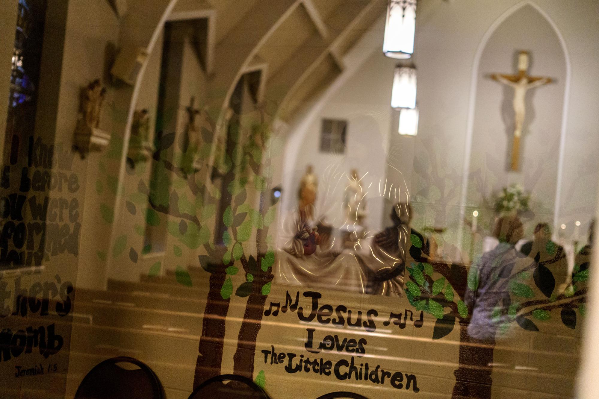 Un mensaje decora un mural que se ve a través de la ventana de una habitación infantil durante la Misa en la Iglesia Católica St. James en Tupelo, Mississippi, el martes 24 de mayo de 2022. Muchas personas en los EE. UU. están reaccionando con horror ante la decisión del Tribunal Supremo sobre el aborto. anulando Roe v. Wade.  Pero en un día que perteneció a los vencedores, millones de personas que han estado inmersas en el movimiento contra el aborto durante el último medio siglo se regocijan.  (Foto AP/David Goldman)