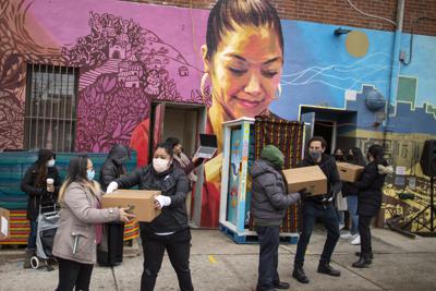 ARCHIVO - En esta fotografía de archivo del 13 de febrero de 2021, voluntarios movilizan despensas de alimentos que serán donadas mietras personas reciben información sobre las vacunas contra el COVID-19 en el centro comunitario Mixteca durante la pandemia de coronavirus en el distrito de Brooklyn, en Nueva York. (AP Foto/Eduardo Munoz Alvarez, Archivo)