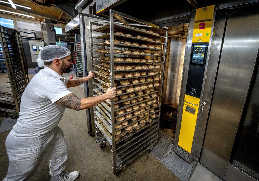 ADDING FULL NAME OF BUSINESS  An employee pushes bread rolls into one of the gas heated ovens in the producing facility in Cafe Ernst in Neu Isenburg, Germany, Monday, Sept. 19, 2022. Andreas Schmitt, head of the local bakers' guild, said some small bakeries are contemplating giving up due to the energy crisis. (AP Photo/Michael Probst)