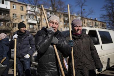 Una mujer llora antes de comenzar a limpiar el sitio en donde un ataque dañó edificios residenciales en Kiev, Ucrania, el viernes 18 de marzo de 2022. (AP Foto/Rodrigo Abd)