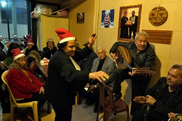 Amira Mansour, center, dances as Samir Damouni playing the Oud during community Christmas dinner for elderly residents at the only majority-Christian Palestinian refugee camp, in Dbayeh, north of Beirut, Lebanon, Wednesday, Dec. 21, 2022. Hundreds of thousands of Palestinians fled or were forced from their homes during the 1948 Mideast war over Israel's creation. Today, several million Palestinian refugees and their descendants are scattered across Jordan, Syria and Lebanon, as well as the West Bank and Gaza, lands Israel captured in 1967. (AP Photo/Bilal Hussein)