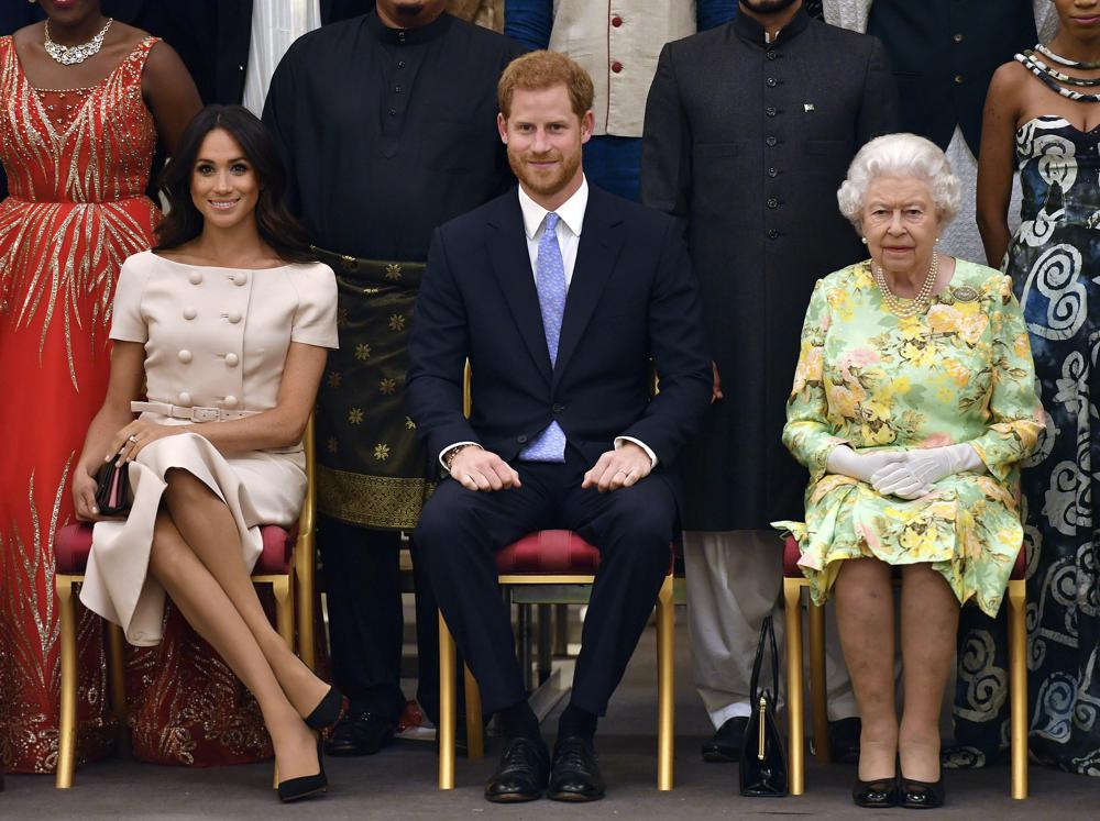 FILE - In this Tuesday, June 26, 2018 file photo, Britain's Queen Elizabeth, Prince Harry and Meghan, Duchess of Sussex pose for a group photo at the Queen's Young Leaders Awards Ceremony at Buckingham Palace in London. Queen Elizabeth II, Britain’s longest-reigning monarch and a rock of stability across much of a turbulent century, has died. She was 96. Buckingham Palace made the announcement in a statement on Thursday Sept. 8, 2022.(John Stillwell/Pool Photo via AP, File)