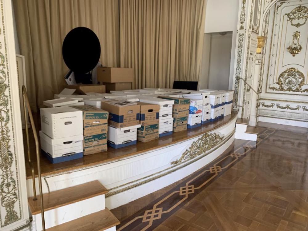 Esta imagen, incluida en la acusación contra el expresidente Donald Trump, muestra cajas de discos almacenadas en el escenario del White and Gold Ballroom en la propiedad de Trump en Mar-a-Lago en Palm Beach, Florida. Trump enfrenta 37 cargos por delitos graves relacionados con el mal manejo de documentos clasificados según una acusación abierta el viernes 9 de junio de 2023. (Departamento de Justicia vía AP)