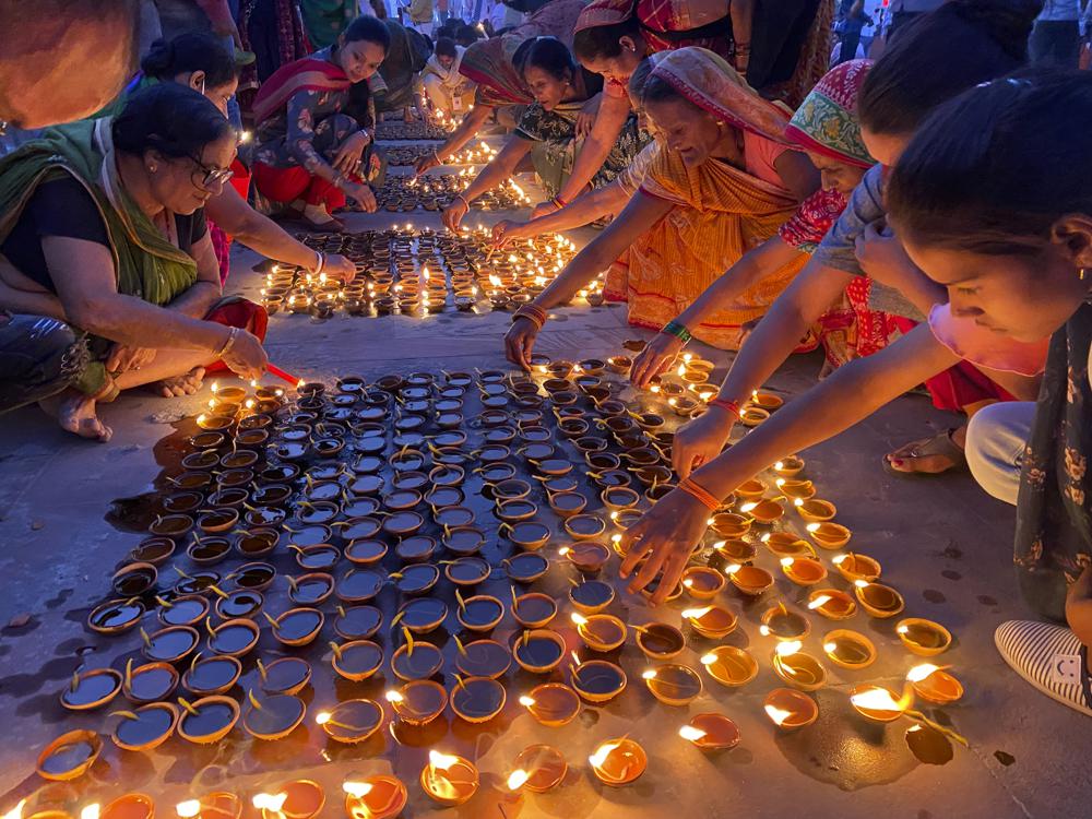 Personas encienden lámparas a orillas del río Saryu en Ayodhya, India, el miércoles 3 de noviembre de 2021. Más de 900.000 lámparas de tierra se encendieron y se mantuvieron encendidas durante 45 minutos mientras la ciudad de Ayodhya, en el norte de India, conservaba su récord mundial Guinness de iluminación. lámparas de aceite como parte de la celebración de Diwali, el festival hindú de las luces. (Foto AP / Rajesh Kumar Singh)