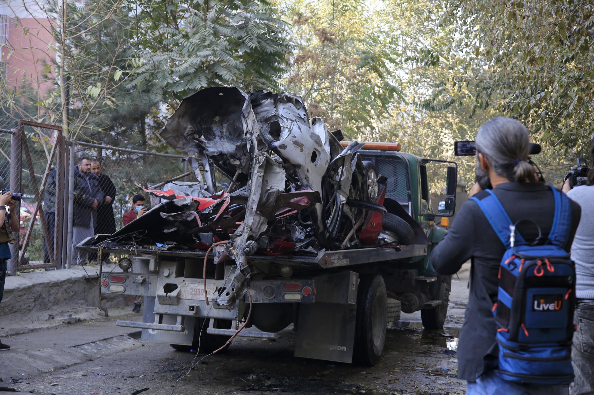 FILE - In this Nov. 7, 2020, file photo, Afghans check car destroyed by an attached bomb in Kabul, Afghanistan. A bomb attached to the vehicle of Yama Siawash, a former presenter on Afghanistan's TOLO TV, exploded killing the journalist and two other civilians, Kabul police said. As the world watches intently for clues on how the Taliban will govern, their treatment of the media will be a key indicator, along with their policies toward women. (AP Photo/Mariam Zuhaib)