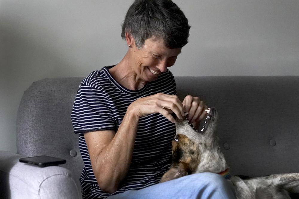 Cyndi Marler plays with her dog, Faith, in her Chicago apartment Wednesday, Oct. 6, 2021. Marler and her husband of over 32 years lived together until March when, following their retirements and the sale of their home, they moved into separate apartments in Chicago to explore life as part of the queer community for the first time. “Being homosexual, you’re just going to go straight to hell. There’s no two ways to it,” Cyndi said of what she and Brad were taught. (AP Photo/Charles Rex Arbogast)