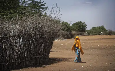FILE - A Somali refugee girl walks past the fence surrounding a hut at Dadaab refugee camp, then hosting over 230,000 inhabitants, in northern Kenya on Dec. 19, 2017. Hundreds of refugees in Kenya's Dadaab camps have been affected by a cholera outbreak as the population in the facilities grows rapidly, a humanitarian charity said Tuesday, May 30, 2023. (AP Photo/Ben Curtis, File)