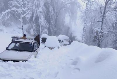 En esta foto proporcionada por Inter Services Public Relations, la gente pasa junto a vehículos atrapados en un área afectada por fuertes nevadas en Murree, a unos 45 kilómetros (28 millas) al norte de la capital de Islamabad, Pakistán, el sábado 8 de enero de 2022. (Inter Services Public Relations vía AP)
