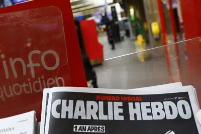 FILE - A special edition of the satirical newspaper Charlie Hebdo that marks one year after, "1 an apres" the attacks on it, on a newsstand Wednesday, Jan. 6, 2016 at a train station in Paris. After the French satirical magazine Charlie Hebdo's launched a cartoon contest to mock Iran's ruling cleric, a state-backed Iranian cyber unit struck back in early January with a hack-and-leak campaign intent on striking fear with the claimed pilfering of a big subscriber database, Microsoft security researchers say. (AP Photo/Francois Mori, File)