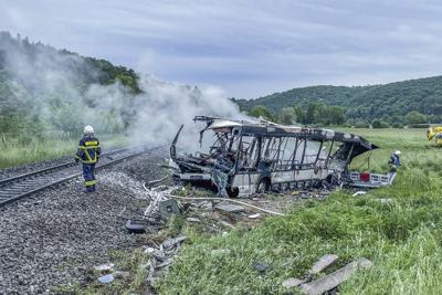 Los bomberos extinguen un incendio en un autobús que chocó con un tren en Blaustein, cerca de Ulm, Alemania, el martes 24 de mayo de 2022. Varias personas resultaron heridas cuando un autobús chocó con un tren en un cruce ferroviario en el sur de Alemania. (Dennis Straub/dpa vía AP)