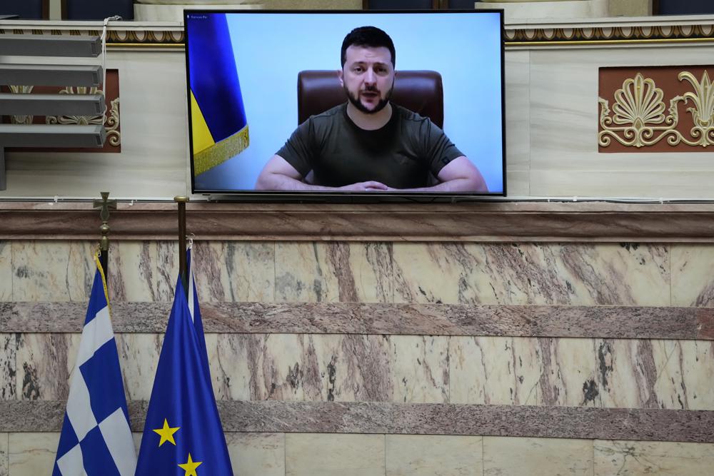 El presidente ucraniano, Volodymyr Zelenskyy, en la pantalla, se dirige al Parlamento griego en Atenas, Grecia, el jueves 7 de abril de 2022. Zelenskyy pidió que se envíen más armas desde Occidente a Ucrania y que se endurezcan las sanciones contra Rusia que prohibirían todas las armas rusas. los bancos hagan negocios en el extranjero y prohibir la entrada de barcos comerciales rusos en puertos de todo el mundo.  (Foto AP/Thanassis Stavrakis)