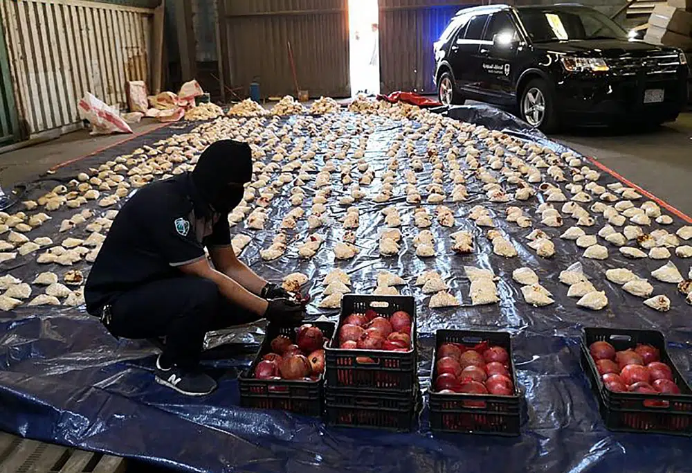 FILE - In this photo released by Saudi Press Agency, a Saudi custom officer opens imported pomegranates, as customs foiled an attempt to smuggle over 5 million pills of an amphetamine drug known as Captagon, which they said came from Lebanon, at Jiddah Islamic Port, Saudi Arabia, Friday, April 23, 2021. A little white pill has given Syrian President Bashar Assad powerful leverage with his Arab neighbors, who have been willing to bring him out of pariah status in hopes he will stop the flow of highly addictive Captagon amphetamines out of Syria. (Saudi Press Agency via AP, File)