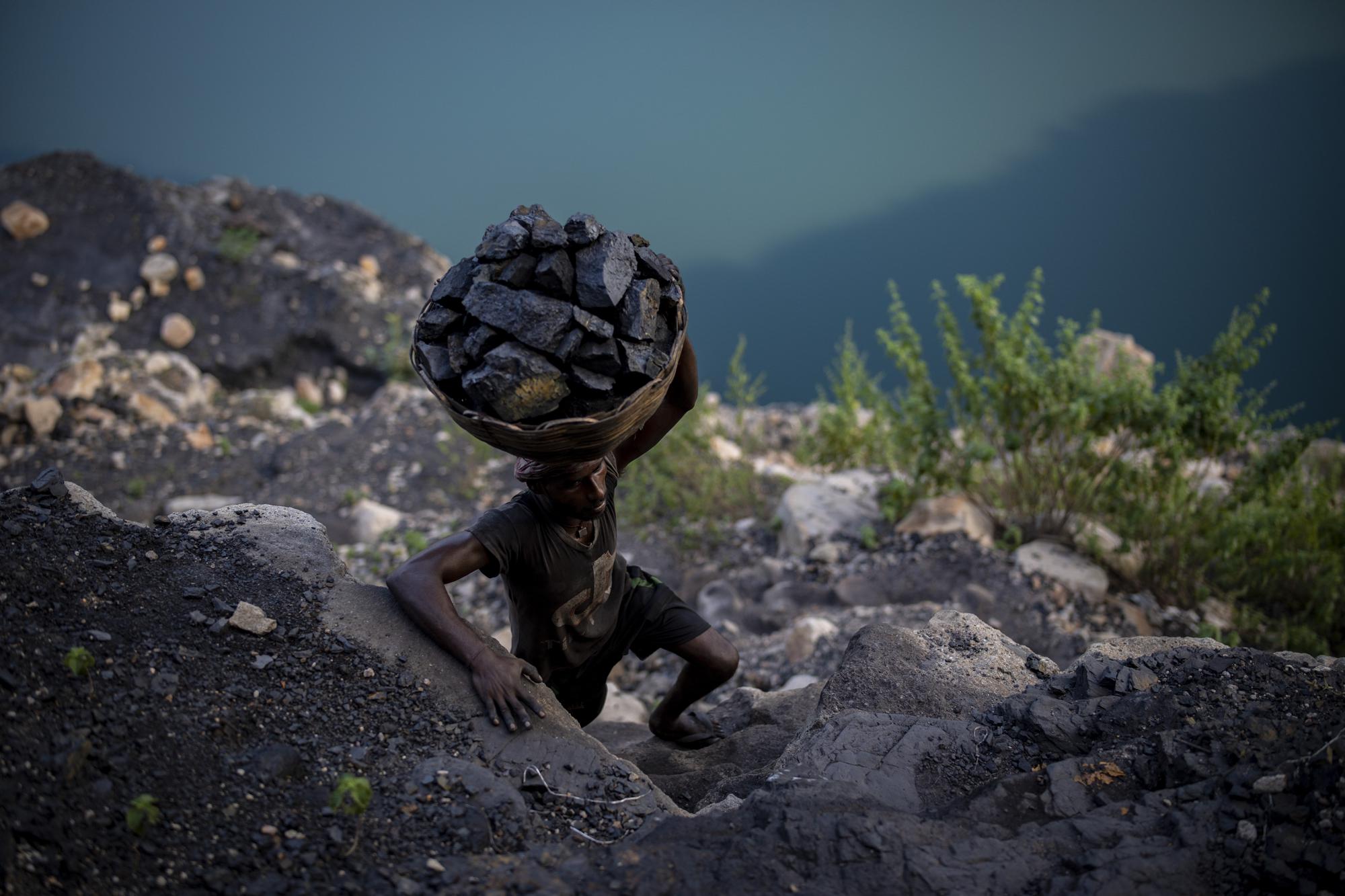 A man climbs a steep ridge with a basket of coal scavenged from a mine near Dhanbad, an eastern Indian city in Jharkhand state, Friday, Sept. 24, 2021. A 2021 Indian government study found that Jharkhand state -- among the poorest in India and the state with the nation’s largest coal reserves -- is also the most vulnerable Indian state to climate change. Efforts to fight climate change are being held back in part because coal, the biggest single source of climate-changing gases, provides cheap electricity and supports millions of jobs. It's one of the dilemmas facing world leaders gathered in Glasgow, Scotland this week in an attempt to stave off the worst effects of climate change. (AP Photo/Altaf Qadri)