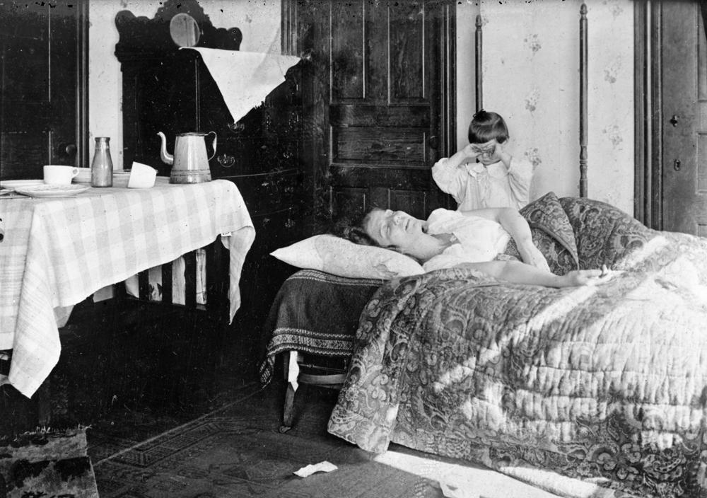 FILE - In this November 1918 photo made available by the Library of Congress, a girl stands next to her sister lying in bed. The girl became so worried she telephoned the Red Cross Home Service who came to help the woman fight the influenza virus. (Library of Congress via AP, File)