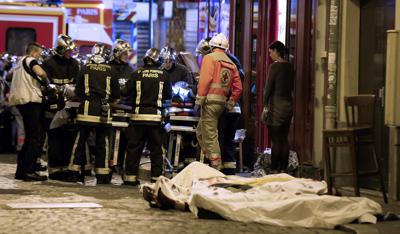 FILE - In this Nov.13, 2015 file photo, medics stand by victims in a Paris restaurant, Friday, Nov. 13, 2015. On Nov. 13, 2015, a cell of nine Islamic State militants armed with automatic rifles and explosive vests left a trail of dead and injured at the national stadium, Paris bars and restaurants and the Bataclan concert hall. Nearly all the attackers were from France or Belgium, as were the cell's 10th member — the only one still alive. He is the chief defendant among 20 people charged in a trial that is expected to last nine months. (AP Photo/Thibault Camus, File)