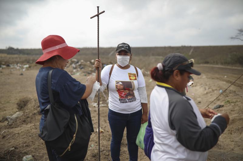 FILE - In this March 11, 2019 file photo, Lidia Lara Tobon, center, whose brother Angel Gabriel Tobon went missing, works with other relatives of the disappeared from the Solecito Collective, as they search for clandestine graves inside a municipal dump after an anonymous source sent the group a map 
suggesting hundreds of bodies were buried in the area, in the port city of Veracruz, Mexico. The mainly female volunteer searchers who fan out across Mexico to dig for the bodies of their murdered relatives are themselves increasingly being killed, putting to the test the government’s promise to help them in their quest for a final shred of justice: a chance to mourn.  (AP Photo/Felix Marquez, File)