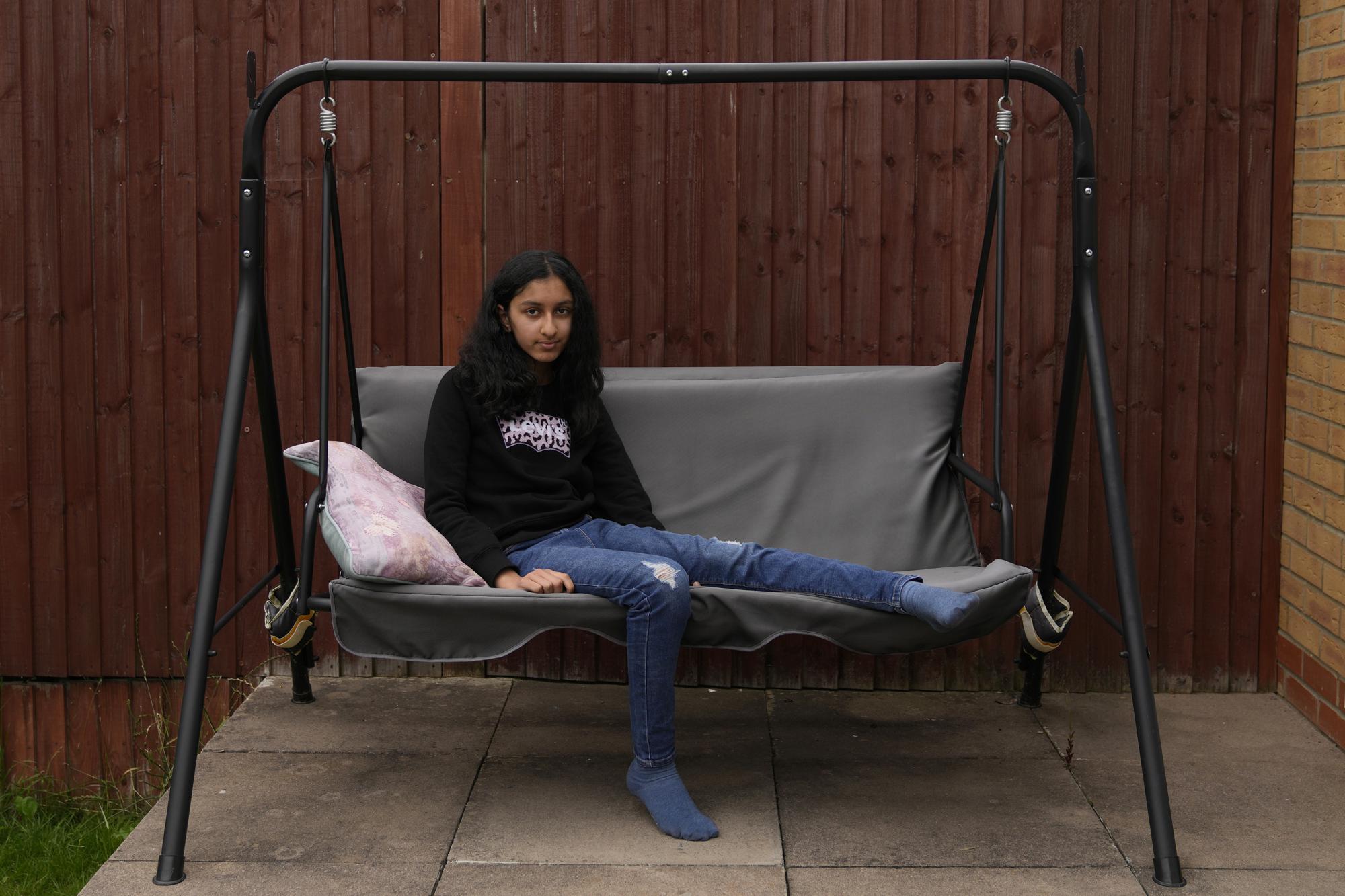 Niva Thakrar, 13, who lost her father to coronavirus, poses at her house in northwestern London, Monday, July 5, 2021. As a way to remember him, she takes the same walks and watches the movies they used to watch together before he died in March after a two-month hospital stay. "I still try to do what we used to do before, but it's not the same," Thakrar said. (AP Photo/Thanassis Stavrakis)