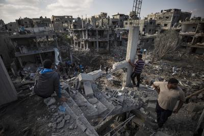 ARCHIVO - En esta imagen de archivo del 14 de mayo de 2021, palestinos miran al lugar donde estaban sus viviendas, destruidas por la noche por ataques aéreos israelíes en la población de Beit Hanoun, en el norte de la Franja de Gaza. Human Rights Watch pidió el lunes 23 de agosto de 2021 que el Ejército israelí mostrara pruebas qye justificaran los ataques, que según el grupo incumplieron las normas de la guerra. (AP Foto/Khalil Hamra, Archivo)