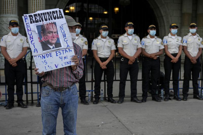 A protestors holds a sign with a portrait of Guatemalan President Alejandro Giammattei outside the National Palace as people attend a rally in support of anti-corruption prosecutor Juan Francisco Sandoval, in Guatemala City, Saturday, July 24, 2021. Sandoval fled Guatemala late Friday, arriving in neighboring El Salvador just hours after he was removed from his post. (AP Photo/Moises Castillo)