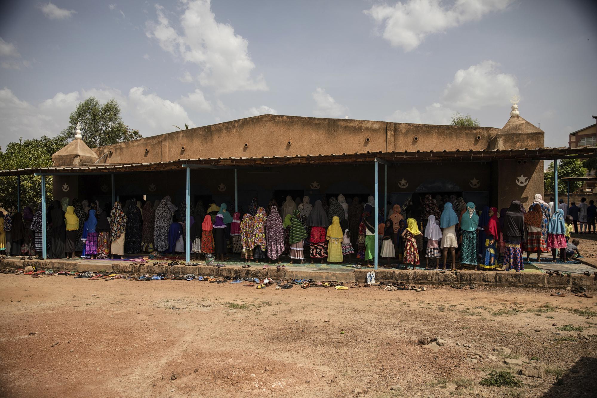 Women join Zenabou Coulibaly Zongo, consultant and founding member of the Council of Burkinabe Women, at the mosque in Ouagadougou, Burkina Faso, Friday, Oct. 29, 2021. Zongo spends her own money making soap and buying hand sanitizer for mosques, markets and health centers. At the start of the pandemic, Zongo, now 63, was hospitalized with bronchial pneumonia. She paid out of pocket for two weeks' worth of oxygen treatments at a private clinic, where she watched others die from respiratory problems. (AP Photo/Sophie Garcia)