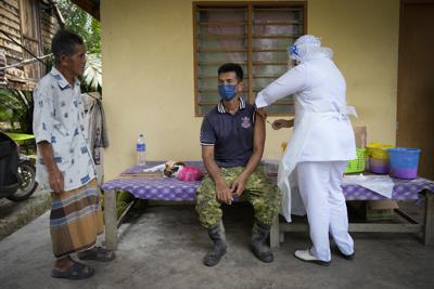 Una enfermera vacuna contra el COVID-19 a un campesino afuera de su casa en Sabab Bernam, una zona rural de Indonesia, el 13 de julio de 2021. (AP Foto/Vincent Thian)