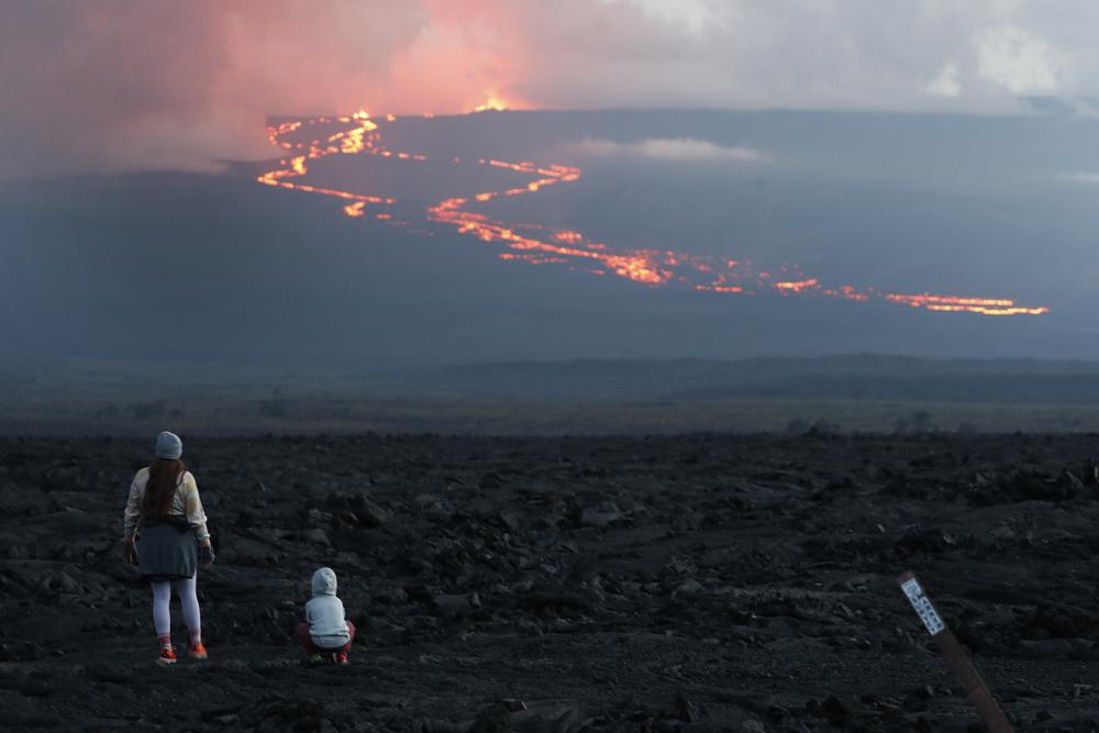 Espectadores contemplan el flujo de lava en la erupción dek volcán Mauna Loa, cerca de Hilo, Hawai, 29 de noviembre de 2022. (AP Foto/Marco Garcia)