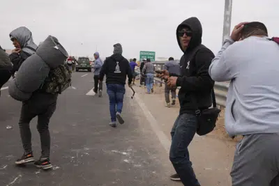 Un migrante se prepara para lanzar una piedra durante un enfrentamiento con la policía antidisturbios peruana en la frontera peruana con Chile, en Tacna, Perú, el sábado 29 de abril de 2023. Una crisis migratoria en la frontera entre Chile y Perú se intensificó desde el jueves cuando cientos de migrantes quedaron varados sin poder cruzar a Perú. (Foto AP/Martín Mejía)