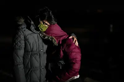 El migrante cubano Mario Pérez abraza a su esposa mientras esperan solicitar asilo luego de cruzar la frontera a Estados Unidos, el viernes 6 de enero de 2023, cerca de Yuma, Arizona. (AP Foto/Gregory Bull)