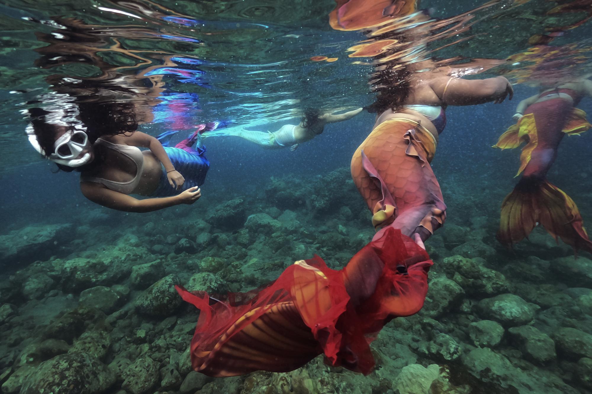 Filipina Jennica Secuya, left, swims with other students during a mermaiding class in Mabini, Batangas province, Philippines on Sunday, May 22, 2022. Away from the critics and chaos of life on land, mer-world is the kinder, gentler and more joyful alternative to the real world. It is also a world, merfolk say, where you can be whoever and whatever you want. (AP Photo/Aaron Favila)
