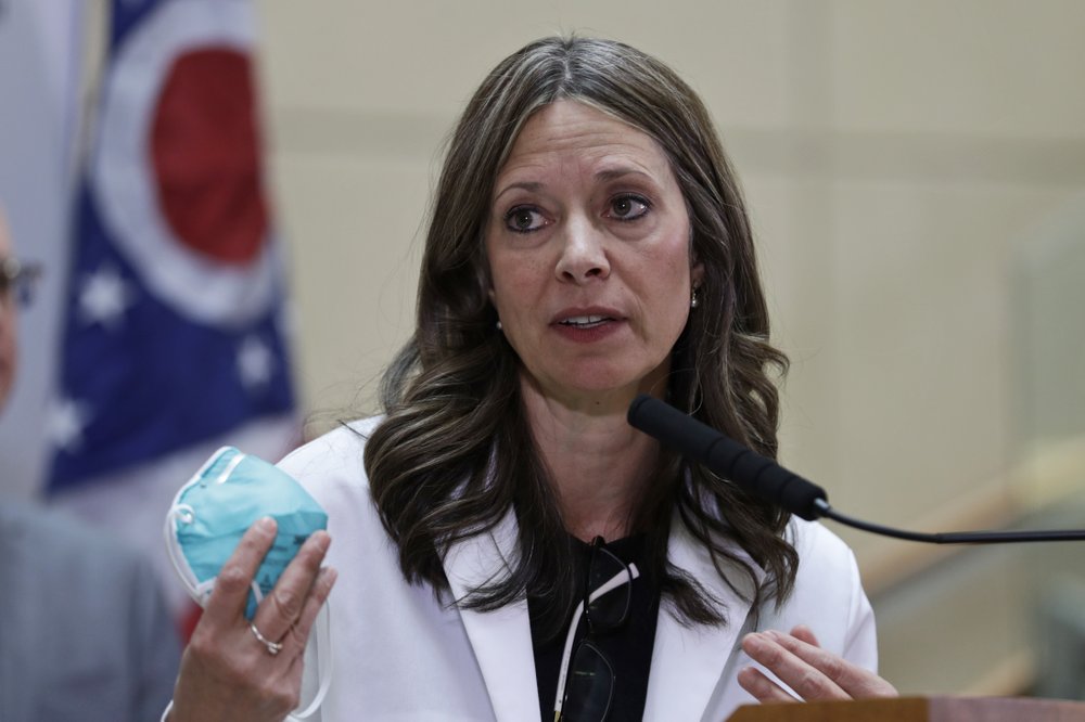 FILE - In this Thursday, Feb. 27, 2020 photo Ohio Department of Health Director Dr. Amy Acton holds up a mask as she gives an update on the state's preparedness and education efforts to limit the potential spread of COVID-19, in Cleveland. Acton, who had a security detail assigned after armed protesters showed up at her home, resigned Wednesday, June 10, 2020. (AP Photo/Tony Dejak)