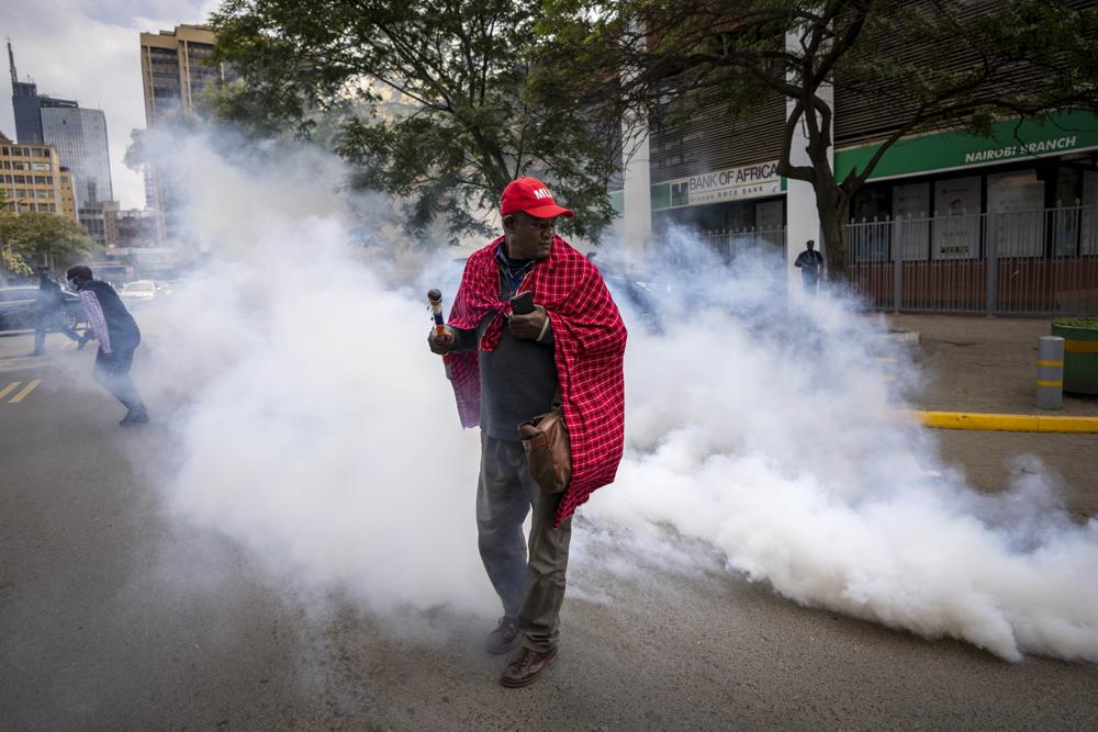 Jonathan Mpute ole Pasha, national coordinator of the Maa Unity Agenda group, is surrounded by tear gas thrown by police to break up a small demonstration of Maasai rights activists outside the Tanzanian high commission in downtown Nairobi, Kenya Friday, June 17, 2022. Tanzania's government is accused of violently trying to evict Maasai herders from one of the country's most popular tourist destinations, the Ngorongoro Conservation Area. (AP Photo/Ben Curtis)