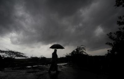 ARCHIVO - Una persona sostiene un paraguas mientras las nubes oscuras se ciernen sobre el distrito de Balasore en Odisha, India, el martes 25 de mayo de 2021, antes de que una poderosa tormenta se dirija hacia la costa oriental. (AP Foto/Archivo)