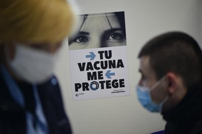 Un hombre espera sentado antes de recibir una dosis de la vacuna de Moderna contra COVID-19 como parte de una campaña de vacunación en San Sebastián, España, el jueves 2 de diciembre de 2021. (AP Foto/Álvaro Barrientos)