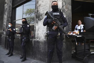 Policías fuertemente armados vigilan las calles del centro de San Salvador, El Salvador, el domingo 27 de marzo de 2022. El Congreso de El Salvador accedió al pedido del presidente Nayib Bukele de declarar el estado de emergencia, en medio de una ola de asesinatos relacionados con pandillas durante el fin de semana. (AP Foto/Salvador Meléndez)