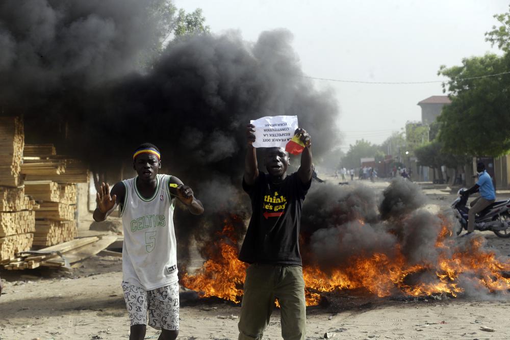 Two men protest on a street in N'Djamena, Chad, Tuesday, April 27, 2021. Thousands of people protested and two people were killed in Chad Tuesday in demonstrations against the rule of a transitional military council headed by the son of the late President Idriss Deby Itno, who was killed last week. (AP Photo/Sunday Alamba)