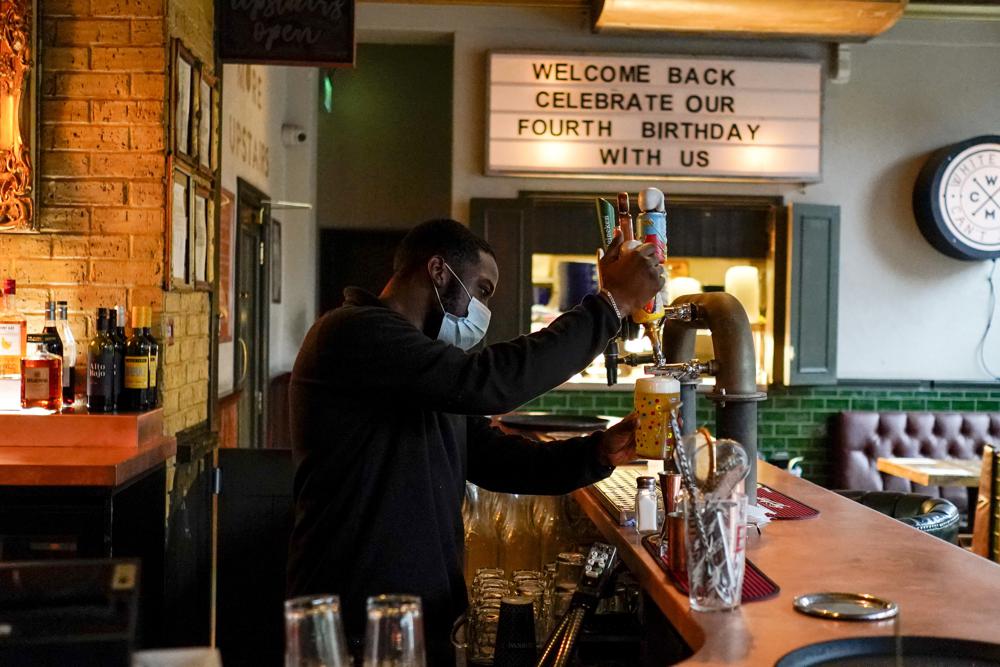 FILE - In this May 17, 2021, file photo, a bartender pours a pint of beer at the Prince of Peckham pub, as it reopens to indoor customers, in London. Coronavirus infections, hospitalizations and deaths are plummeting across much of Europe. Vaccination rates are accelerating, and with them, the promise of summer vacations. (AP Photo/Alberto Pezzali, File)