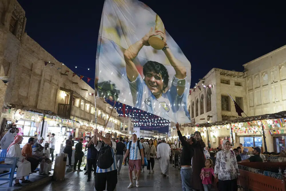 Un hincha de Argentina flamea una bandera con la imagen del astro Diego Maradona en el mercado Souq Waqif de Doha, Qatar, Martes diciembre 15, 2022. Argentina enfrentará a Francia en la final del Mundial el 18 de diciembre. (AP Foto/Andre Penner)