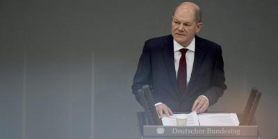 German Chancellor Olaf Scholz delivers a speech on the Russian invasion of the Ukraine during a meeting of the German federal parliament, Bundestag, at the Reichstag building in Berlin, Germany, Sunday, Feb. 27, 2022. The reflections are caused by a metallic handrail at the press tribune. (AP Photo/Michael Sohn)