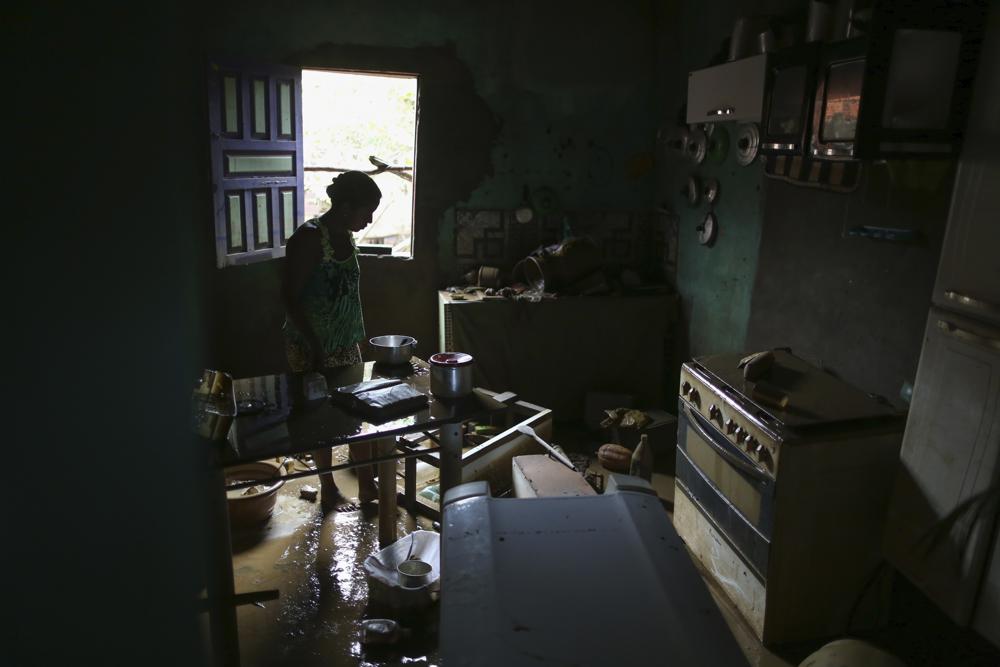 A woman cleans her house that was flooded in Itapetinga, Bahia state, Brazil, Tuesday, Dec. 28, 2021. Two dams broke Sunday in northeastern Brazil, threatening worse flooding in a rain-drenched region that has already seen thousands of forced to flee their homes. (AP Photo/Raphael Muller)