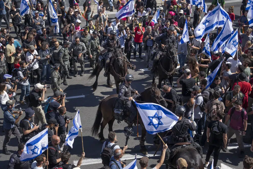 Israeli mounted police officers disperse demonstrators blocking a highway during a protest against plans by Prime Minister Benjamin Netanyahu's government to overhaul the judicial system in Tel Aviv, Israel, Thursday, March 16, 2023. (AP Photo/Oded Balilty)