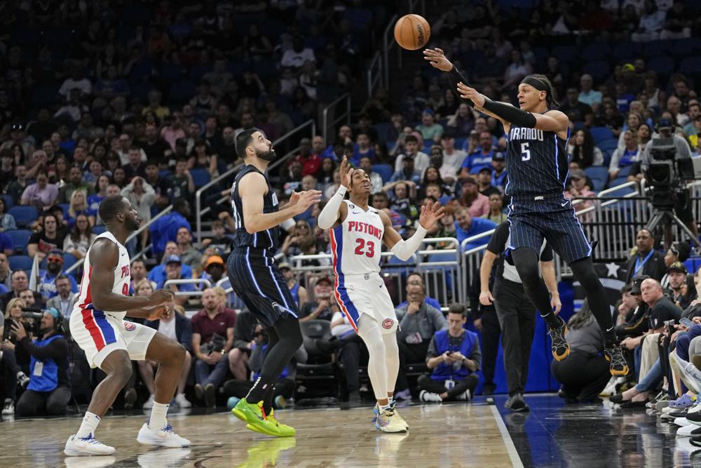 Orlando Magic's Paolo Banchero (5) saves the ball from going out of bounds in front of teammate Goga Bitadze, center, and Detroit Pistons' Jaden Ivey (23) and Eugene Omoruyi, left, during the first half of an NBA basketball game, Sunday, April 2, 2023, in Orlando, Fla. (AP Photo/John Raoux)