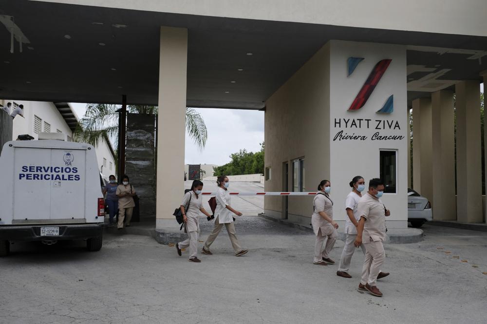 Trabajadores de un hotel salen de él cuando un vehículo policial ingresa luego de un enfrentamiento armado, el jueves 4 de noviembre de 2021, cerca de Puerto Morelos, México.  (Foto AP / Karim Torres)