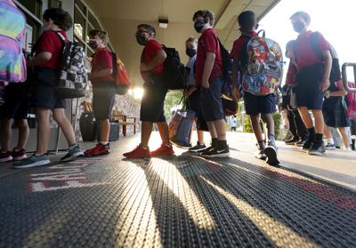 Estudiantes de primaria con mascarillas para prevenir la propagación del COVID-19 entran a la escuela el primer día de clases en Richardson, Texas, 17 de agosto de 2021. El distrito escolar desafió el decreto del gobernador Greg Abbott que prohíbe a los distritos imponer el uso de la mascarilla. Abbott ha dado positivo para el coronavirus.  (AP Foto/LM Otero)