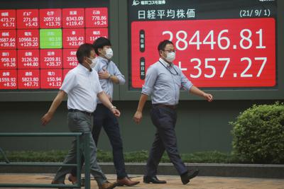 Un grupo de personas frente a una cartelera financiera en Tokio el 1 de septiembre del 2021. (AP Foto/Koji Sasahara)
